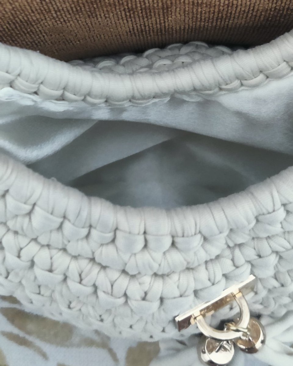 Interior de un bolso tejido, con forro de tela y broche metálico
