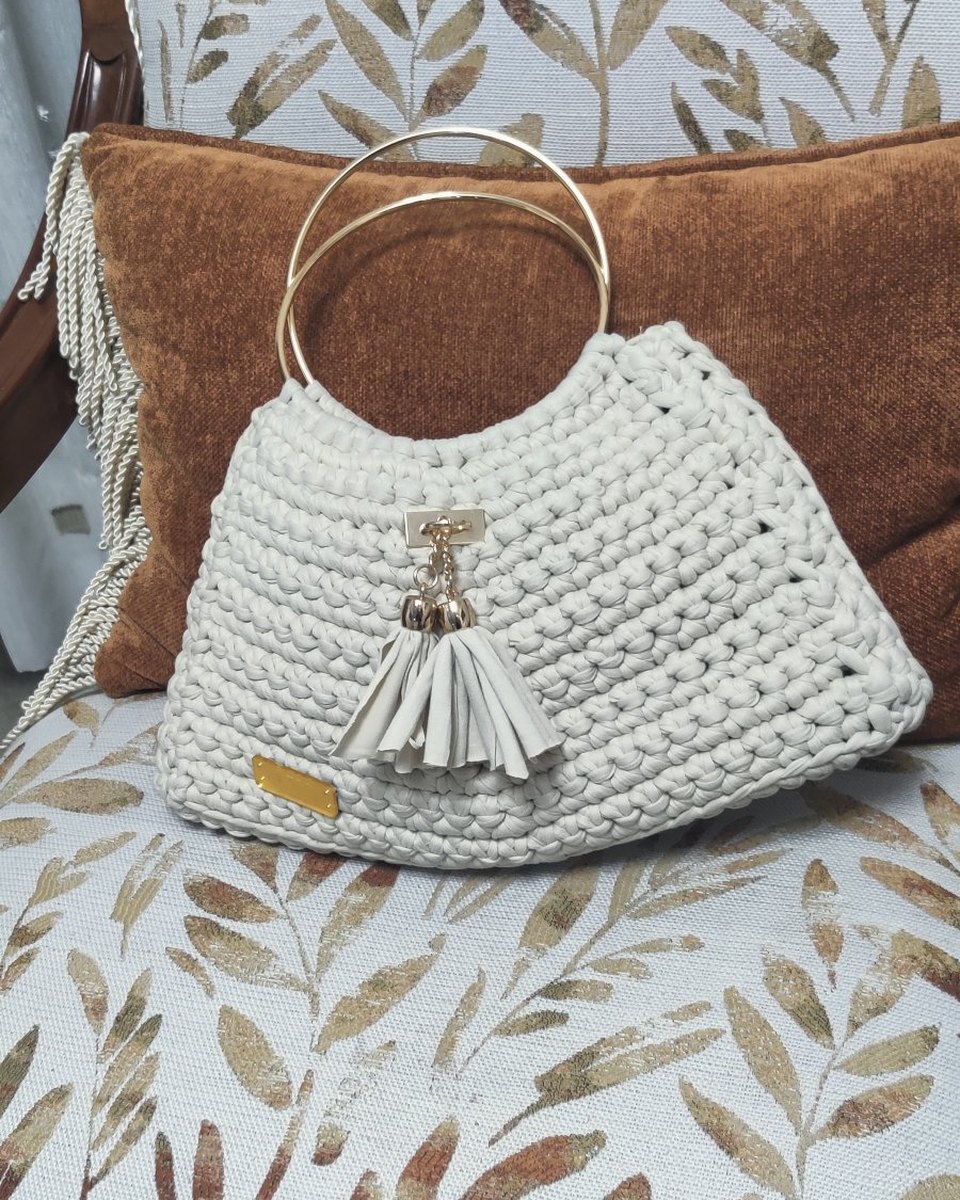 Bolso tejido color perla con asas de aro dorado y borla